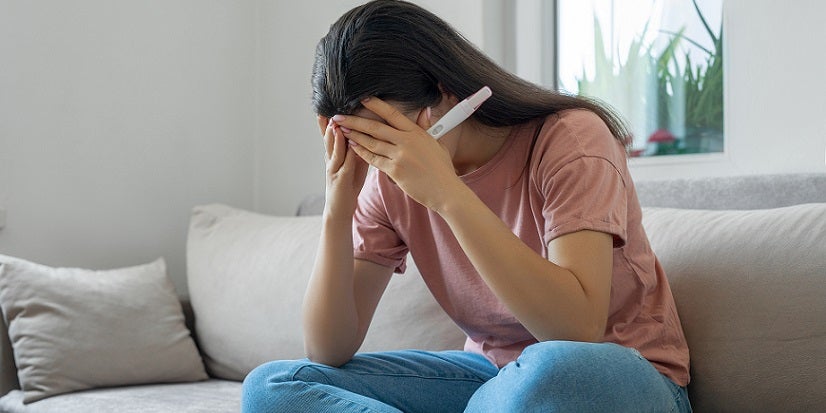 Sad woman with pregnancy test