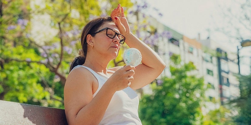 Woman with fan on bench outside