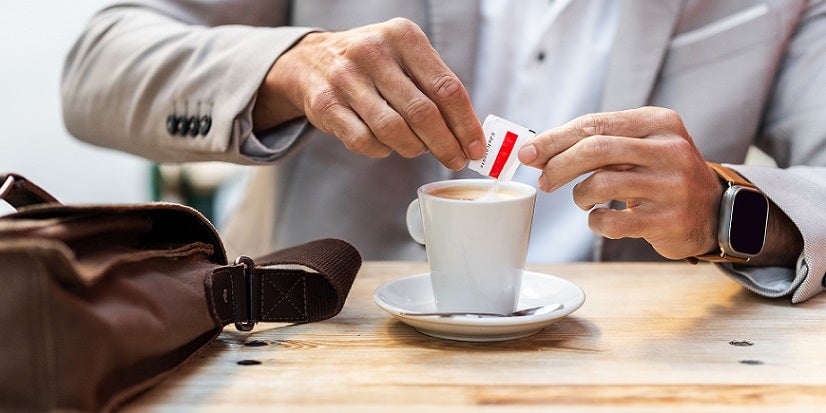 Person putting sugar in coffee